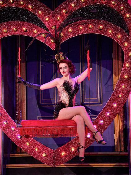 a woman sitting on top of a red bench in front of a heart shaped sign