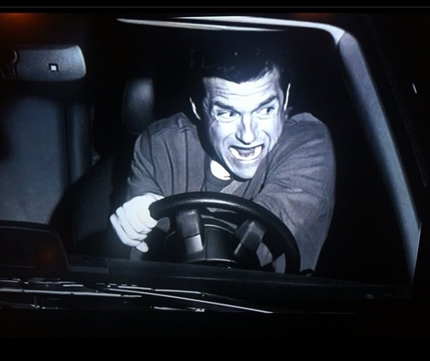 a man is driving in the dark with his hands on the steering wheel and smiling