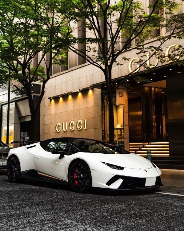 a white sports car is parked in front of a building with the word gucci on it