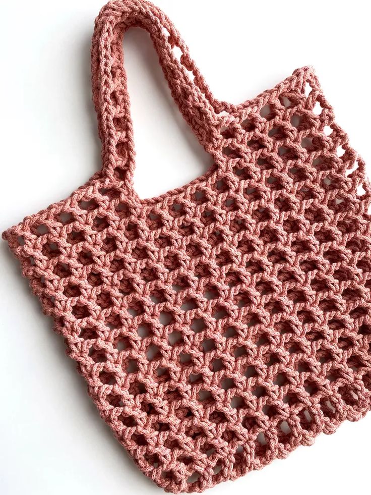 a pink crocheted bag sitting on top of a white table