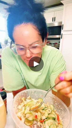 a woman with blue hair and glasses is looking at a bowl of food on the table