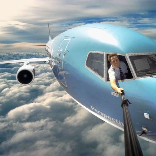 a man is looking out the window of an airplane in the sky with clouds below