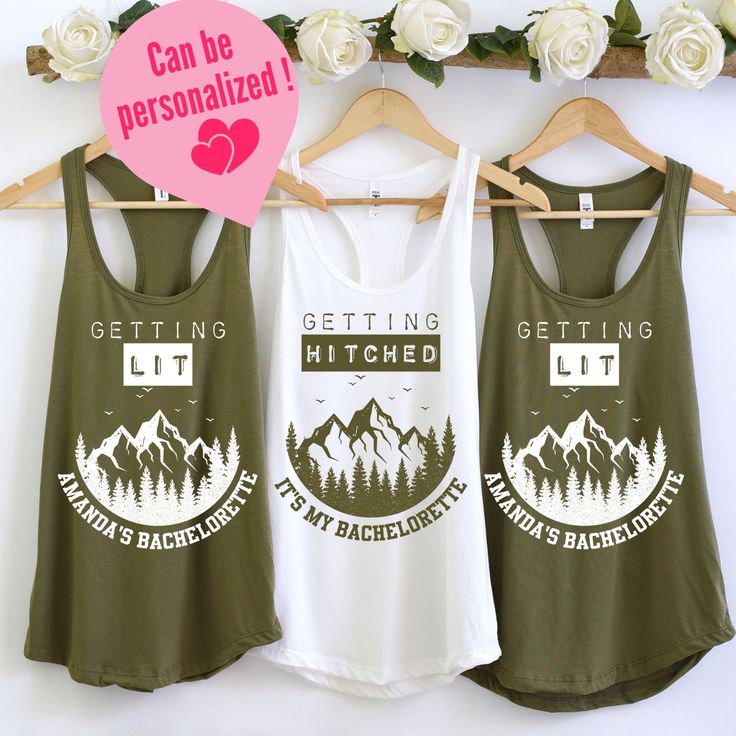 three tank tops hanging on a rack with flowers in the background and white roses behind them