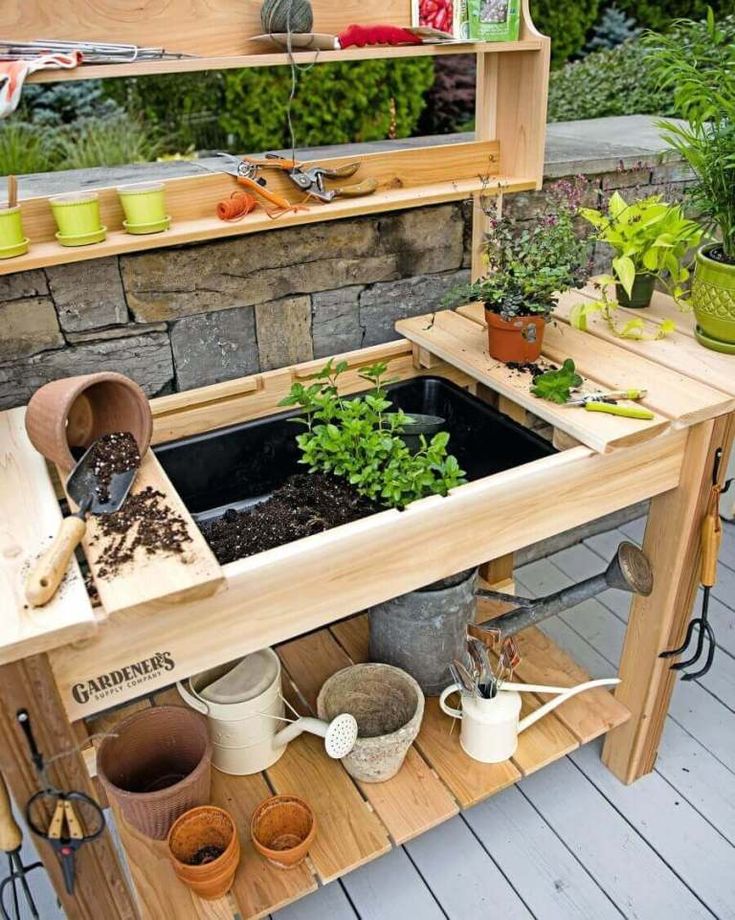 an outdoor garden area with potted plants and gardening tools on a wooden table outdoors