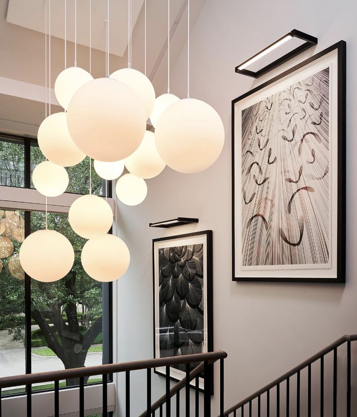 a staircase with art hanging from the ceiling and pictures on the wall next to it