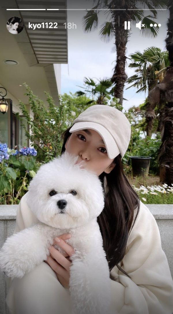 a woman is holding a white dog in her arms while wearing a hat and coat