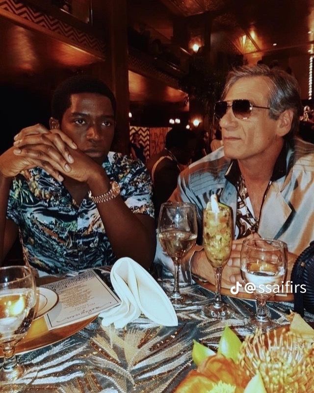 two men sitting at a table with wine glasses