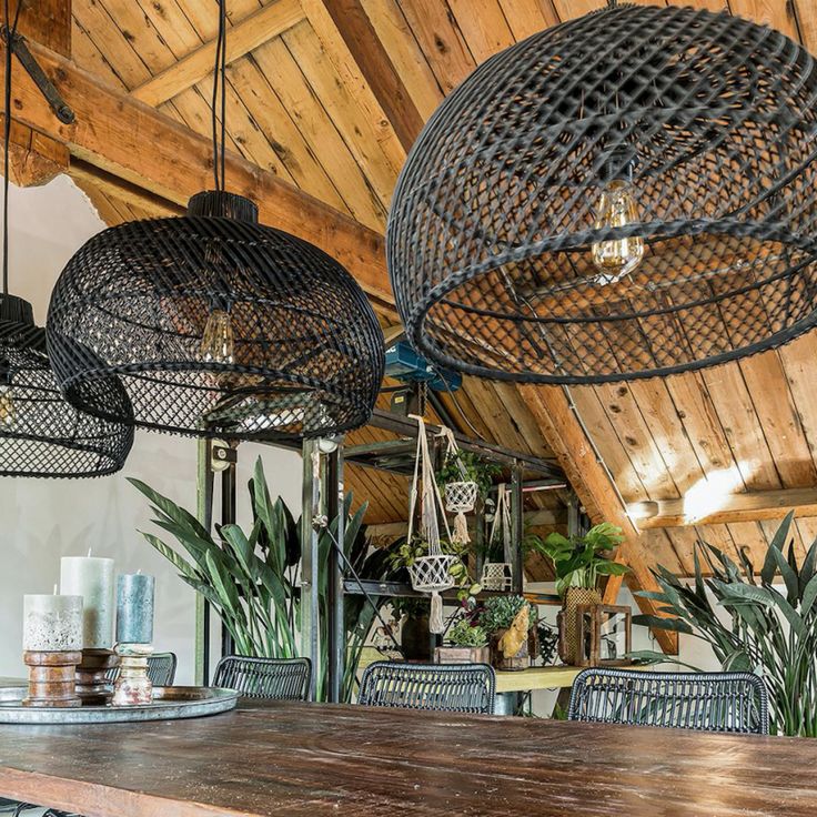 a wooden table topped with lots of chairs under hanging lights over it's head