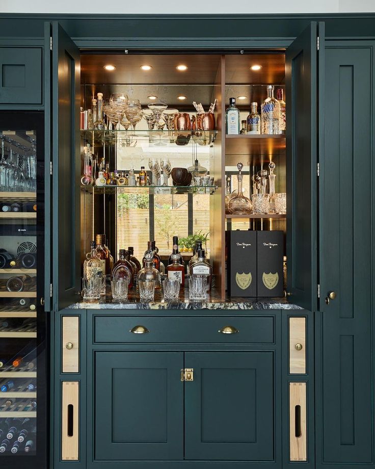 a green cabinet filled with lots of bottles and glasses next to a wine glass case