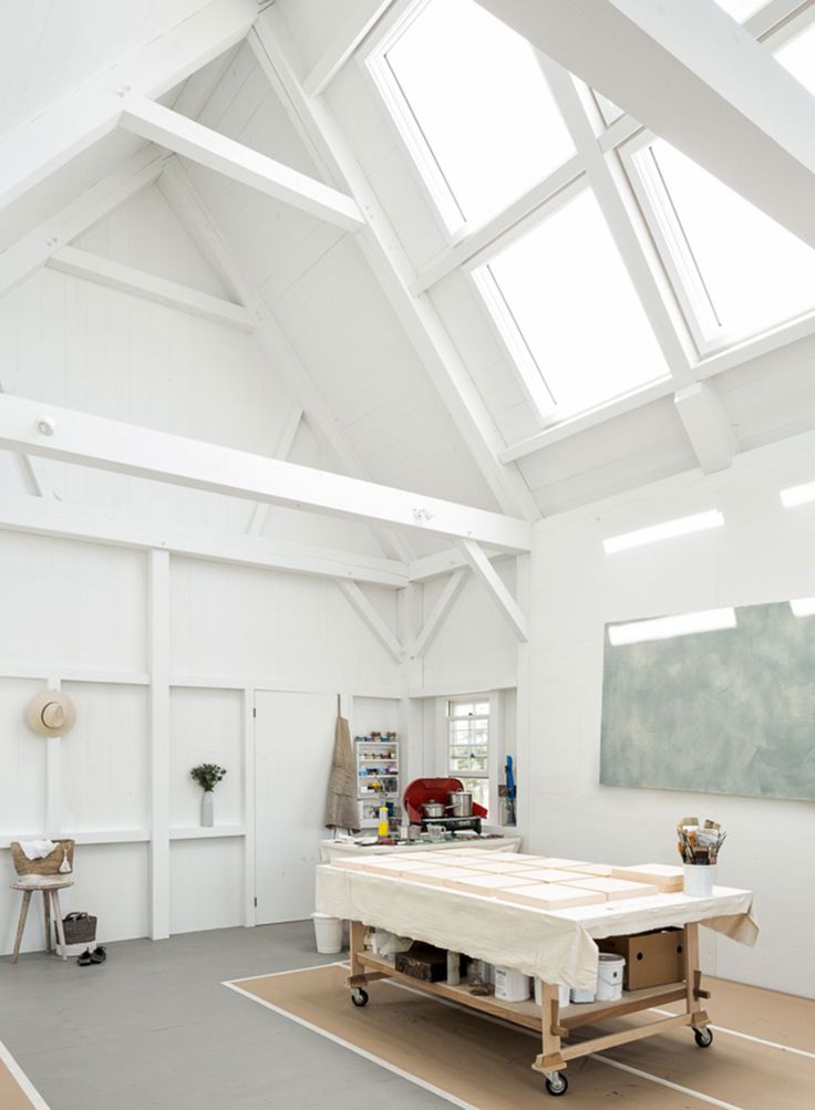 an empty room with a table and chairs in the center, under a skylight