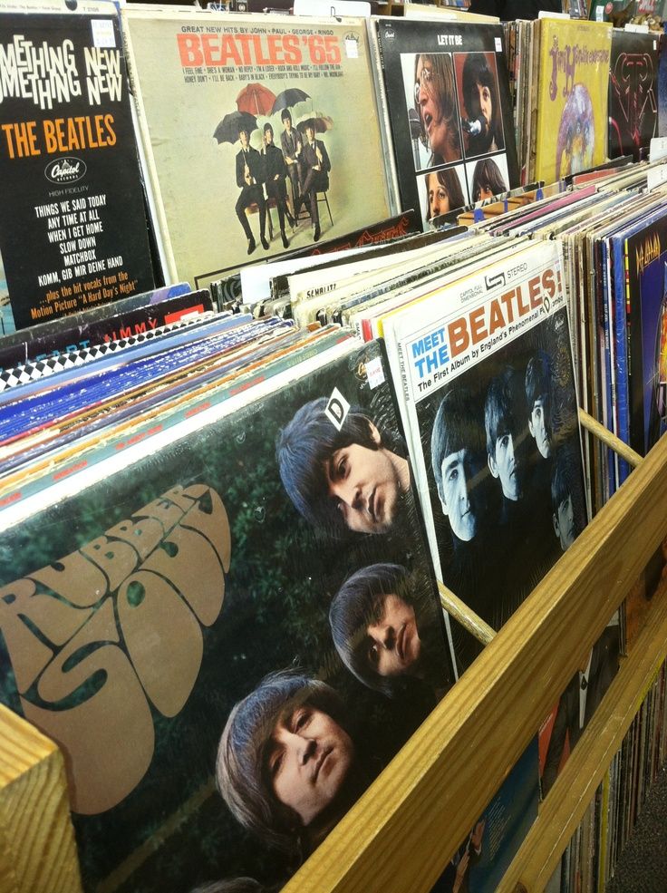 the beatles album covers are on display in a record store's shelves, and they are lined up against each other