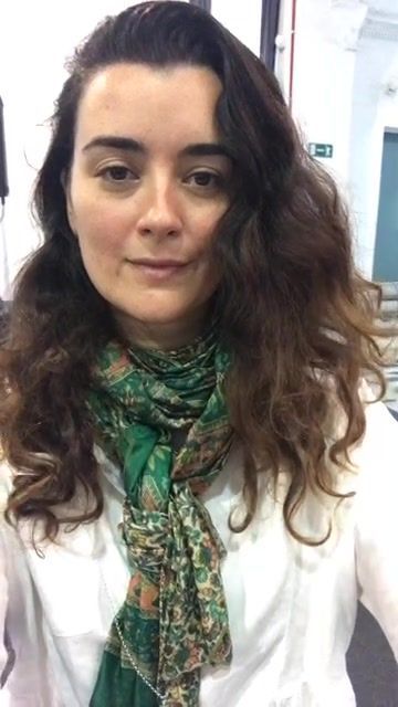 a woman with long hair wearing a white shirt and green scarf in an office setting