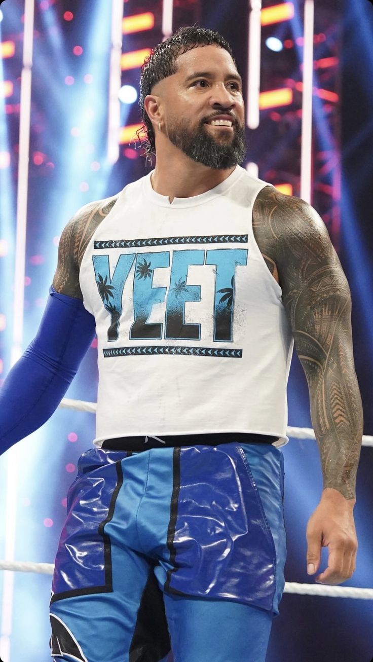 the wrestler is wearing blue shorts and a white t - shirt