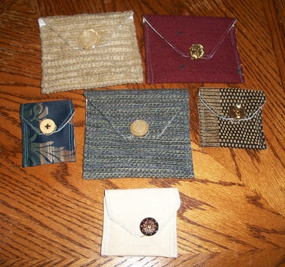 four different colored envelopes sitting on top of a wooden table next to a button