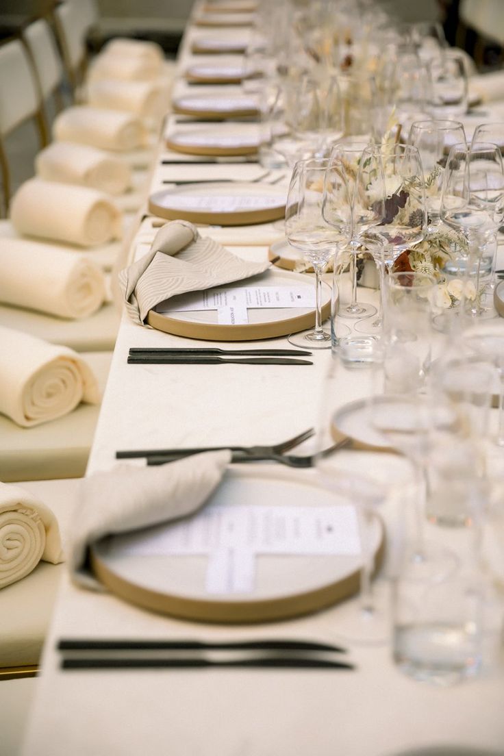 a long table is set with place settings, napkins and glasses for dinner guests