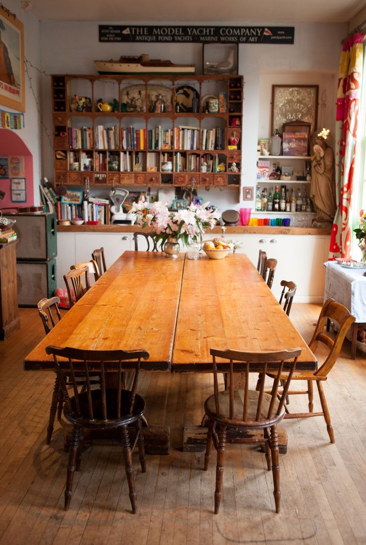 an old fashioned dining room table and chairs with bookshelves in the background,