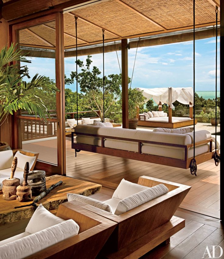 a living room filled with furniture next to a large glass window overlooking the ocean and trees