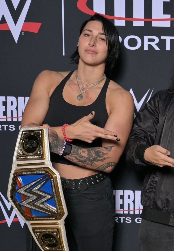 a woman holding a wrestling belt in her hands