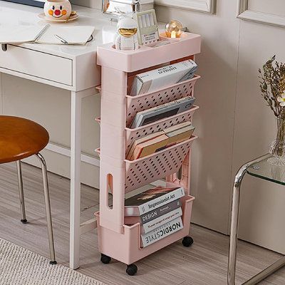 a pink cart with lots of books on top of it in front of a desk