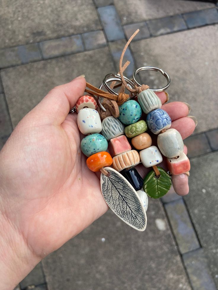 a hand holding a bunch of different colored beads with leaves attached to the bead