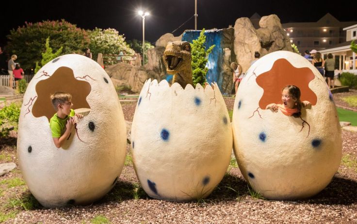 three children are playing in fake eggs at the park