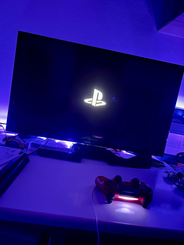 a video game console sitting on top of a desk next to a neon purple wall