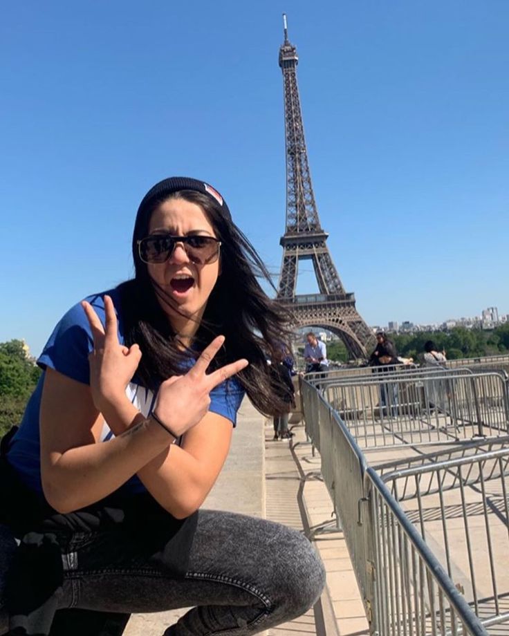 a woman poses in front of the eiffel tower