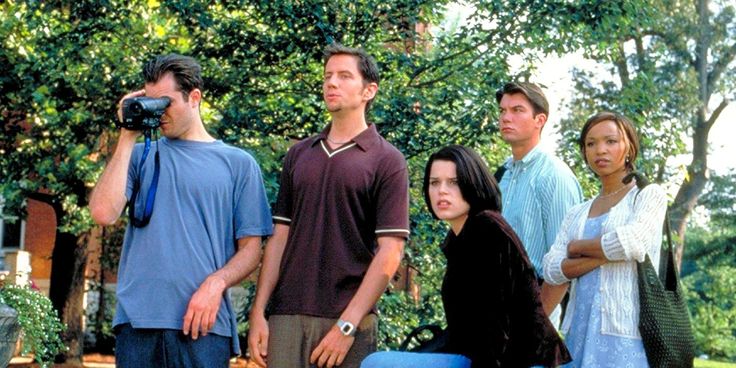 a group of people standing next to each other in front of a wall and trees