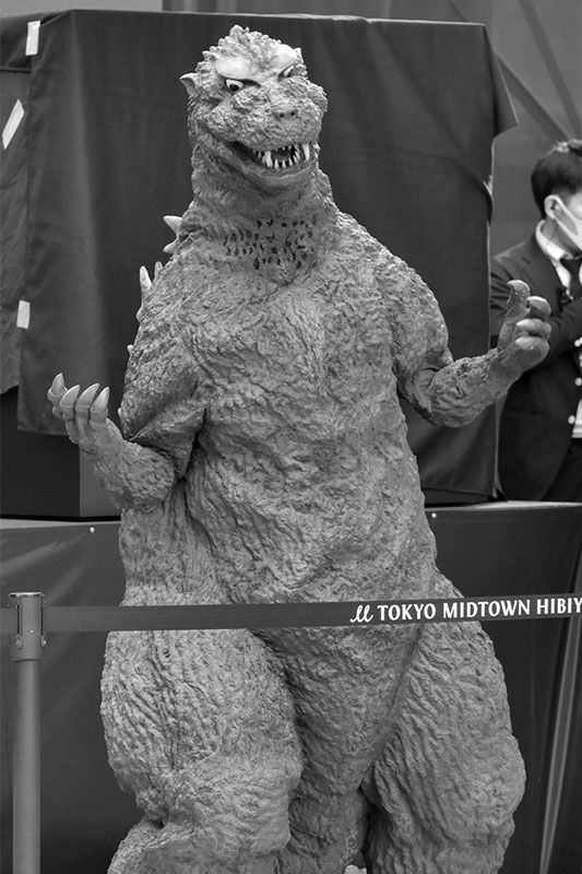 a godzilla statue is standing in front of a crowd