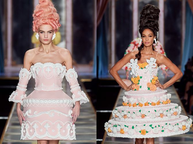 two models on the runway in dresses made out of cakes and flowers, one is wearing a pink wig