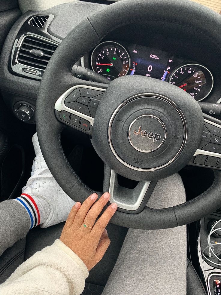 a woman driving a car with her hands on the steering wheel and dashboard lights showing