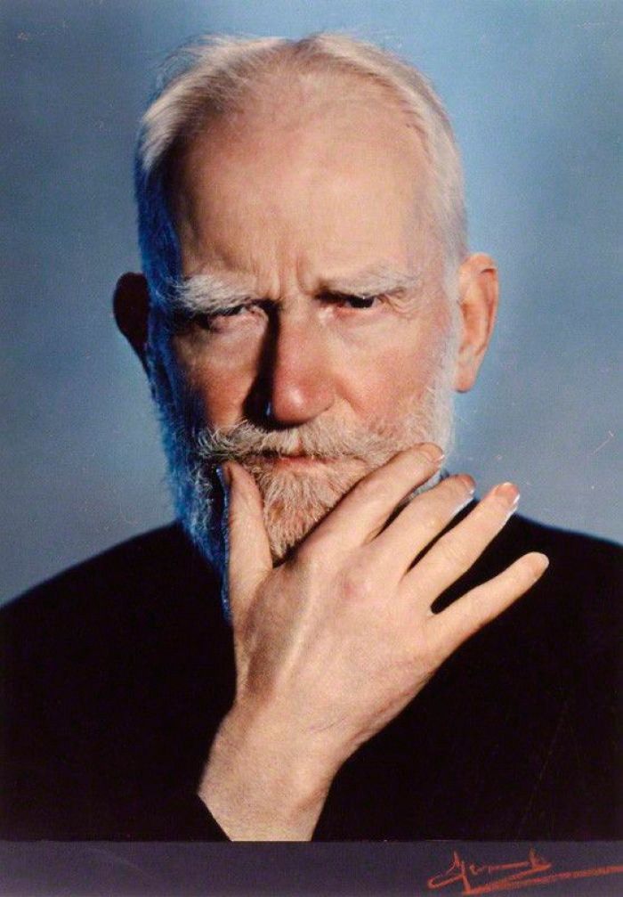 an older man with white hair and a beard is posing for a photo in front of a blue background