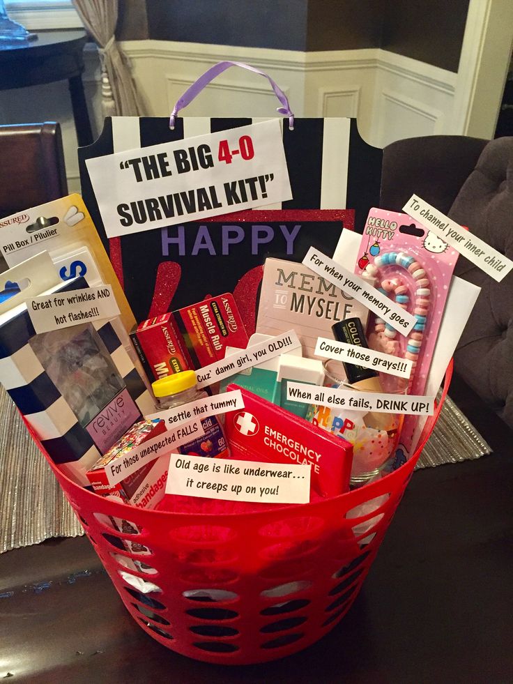 a red basket filled with lots of items sitting on top of a table next to a sign that says the big 40 survival kit happy