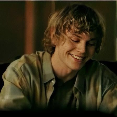 a smiling young man sitting at a table