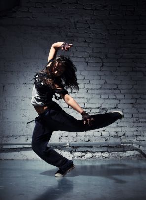 a woman is dancing in front of a brick wall