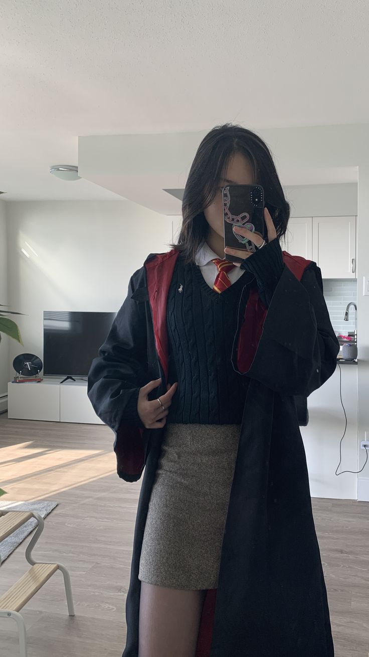 a woman is taking a selfie with her cell phone in the living room while wearing a skirt and jacket