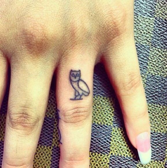a small owl tattoo on the middle finger