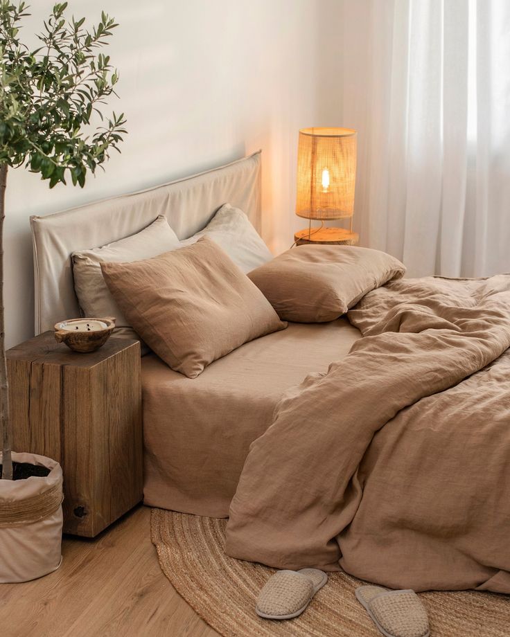 a bed that has some pillows on top of it and a potted plant in the corner