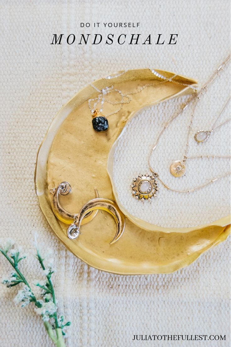 two necklaces sitting on top of a crescent shaped plate next to a small flower