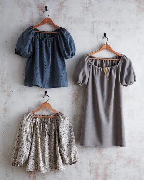 three blouses hanging up against a wall, one in grey and the other in blue