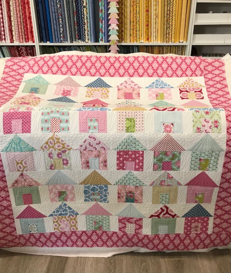 a quilt is on display in front of some bookshelves and other colorful fabrics