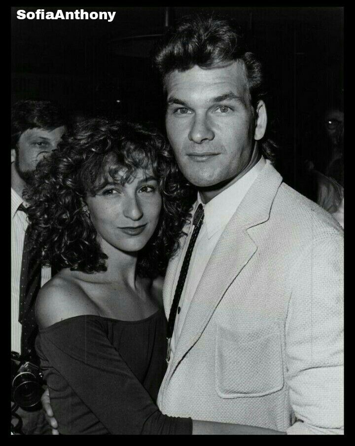 black and white photograph of man and woman posing for the camera in front of other people