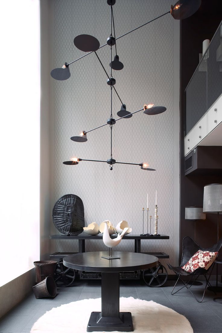 a living room filled with furniture and a chandelier hanging from the ceiling over a table