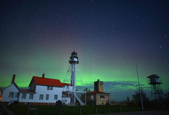 a lighthouse with the aurora in the background
