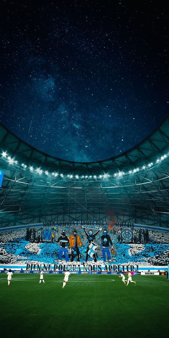 soccer players are on the field in front of an empty stadium at night with stars overhead