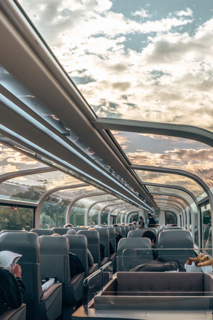 the inside of a bus with people sitting on seats and looking out the window at the sky
