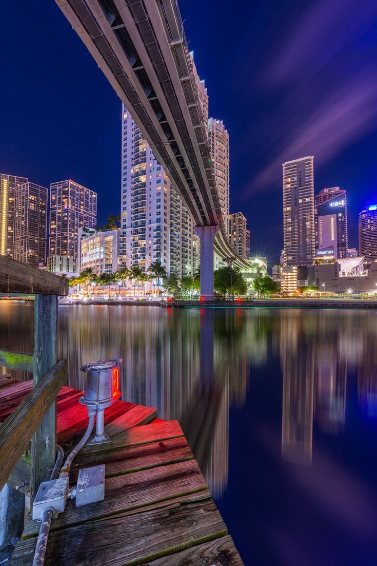 the city skyline is lit up at night with lights reflecting in the water and buildings on either side