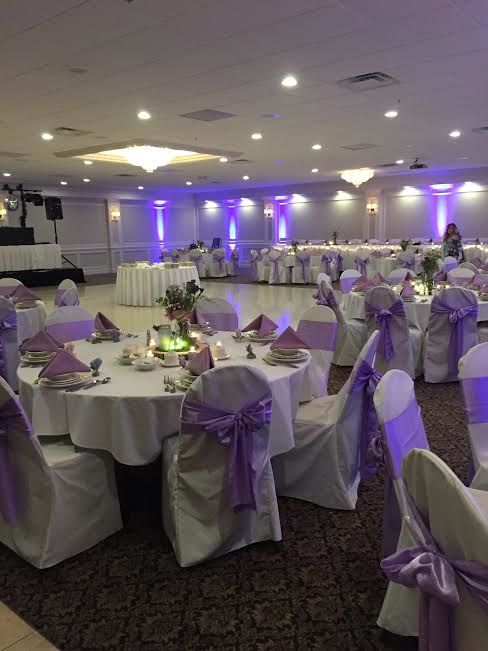 the banquet room is set up with white linens and purple sashes on tables