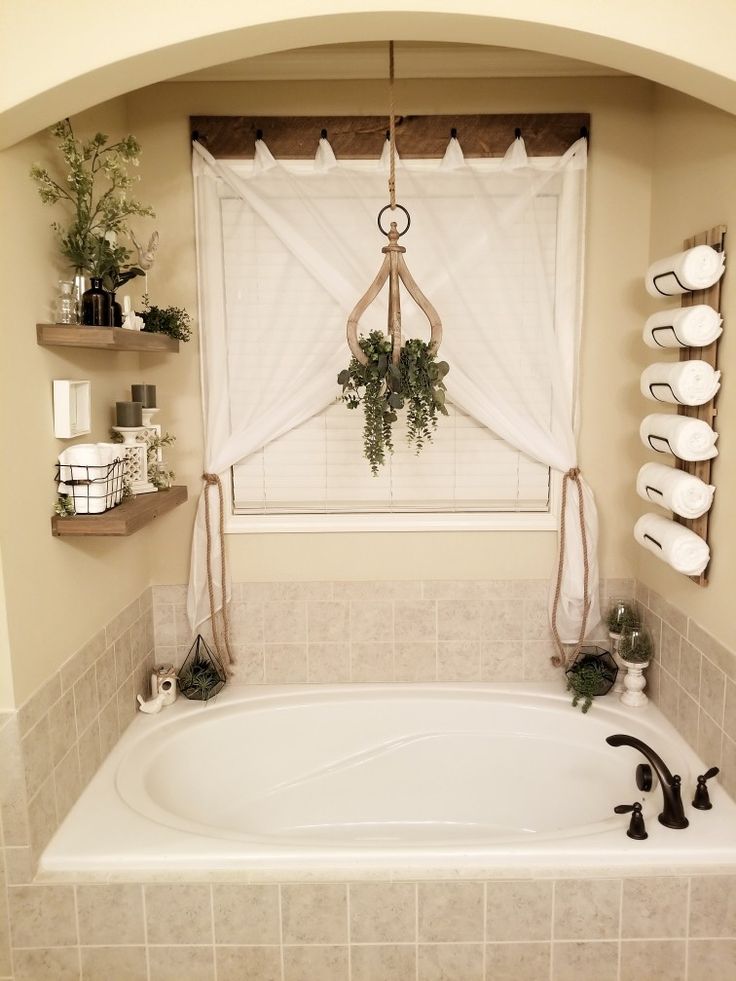 a bath tub sitting under a window next to a shelf filled with potted plants
