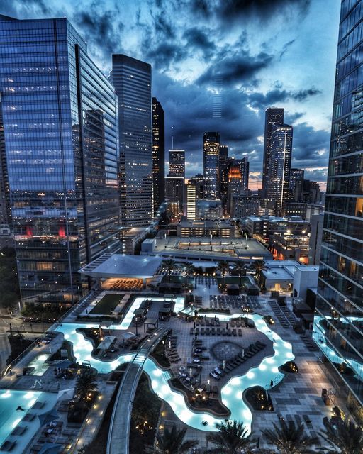 an aerial view of a city at night with skyscrapers and water features in the foreground